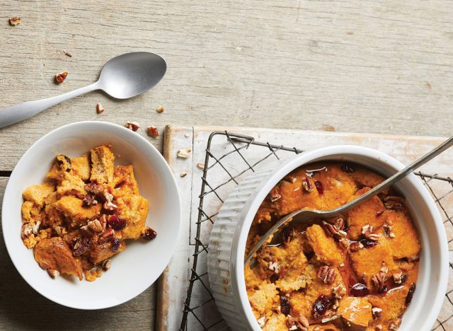 deux bols de pudding au pain à la citrouille avec des cuillères sur une grille et un fond de bois