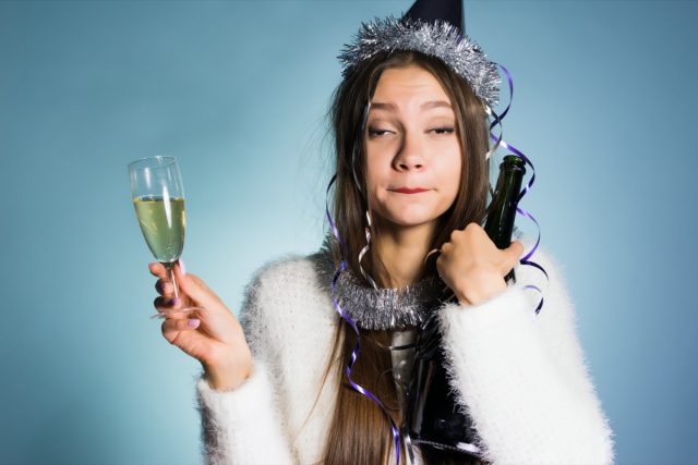 femme ivre dans une casquette festive tenant du champagne dans les mains