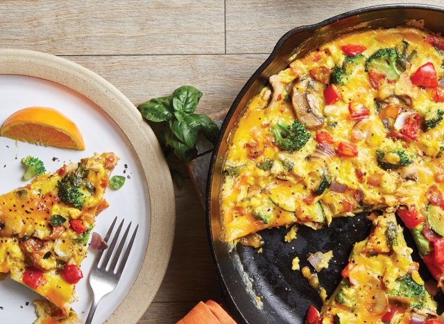 frittata de légumes chargés dans une poêle en fonte avec tranche sur assiette et fourchette