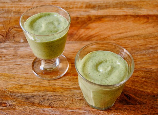 smoothie vert dans deux verres sur une surface en bois